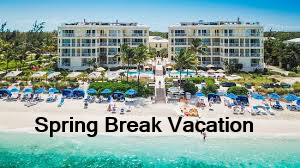 Aerial view of a beach resort with poolside loungers and umbrellas, surrounded by greenery, during a clear day.